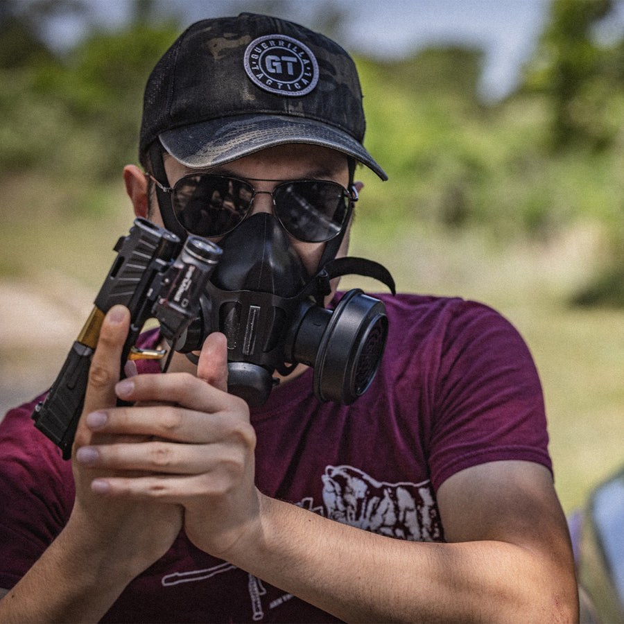 Medium head on shot of a man with sunglasses and a hat, wearing the TAPR mask with the filter on the left side.