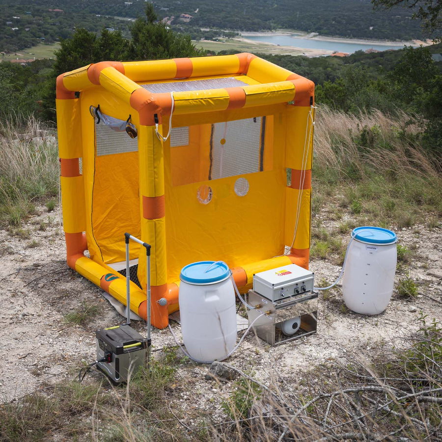 side view of the decontamination shower with the water barrels, hoses, control box and battery in view