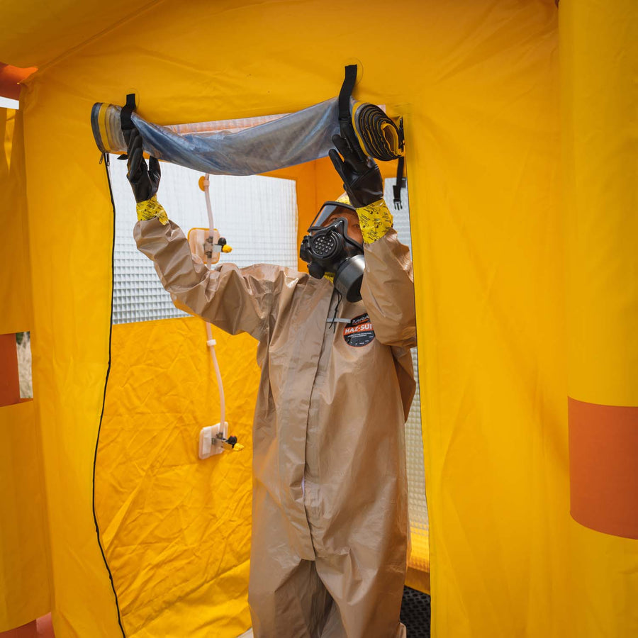 man in hazmat suit rolling down the decontamination shower's entry cover.